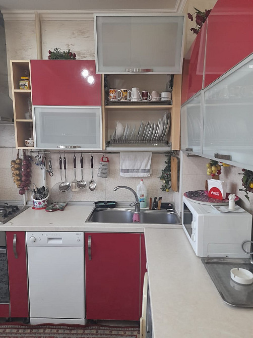 Кухня с красными мебельными фасадами и посудой