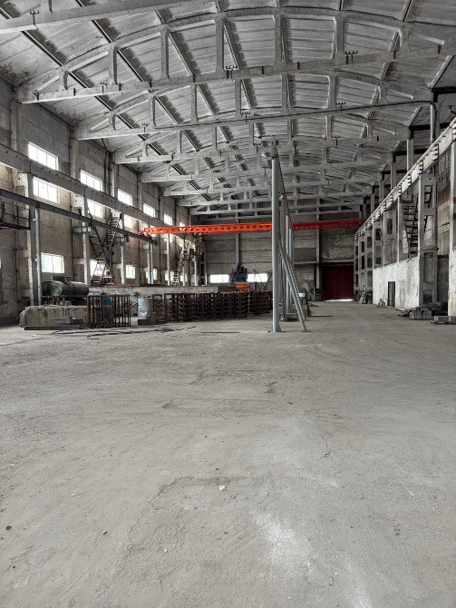 Жоғары төбелер мен құрылыс техникасымен жабдықталған өнеркәсіп ғимараты ішінен