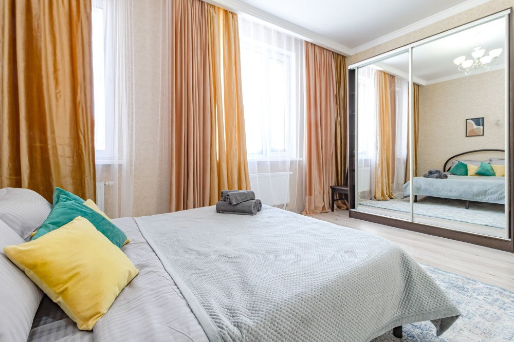 Спальная комната с зеркалом и светлыми шторами