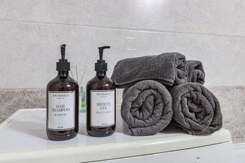 Шампунь и гель для душа на белом фоне с полотенцами