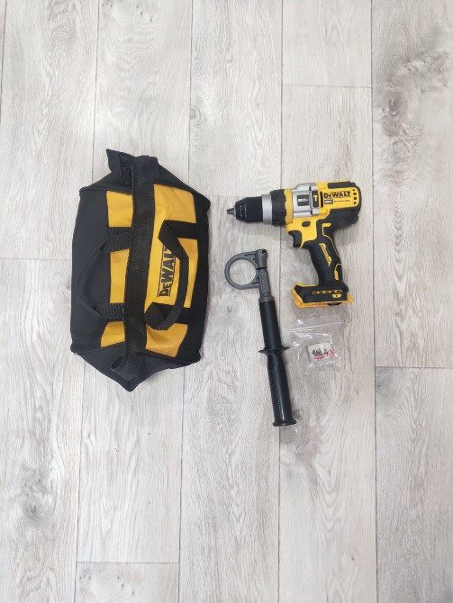 Электродрель Dewalt с аксессуарами и сумкой для инструментов, расположенные на деревянном полу