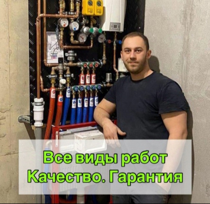 Молодой мужчина стоит рядом с трубопроводами и оборудованием, рекламирующим услуги сантехники