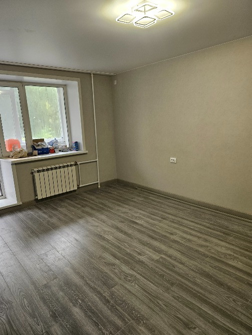 Просторная комната с серым полом и большими окнами