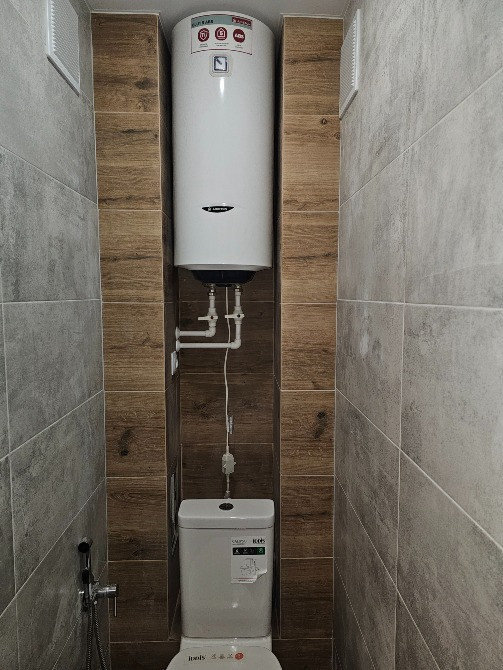 Установка с бойлером и унитазом, отделка плиткой в ванной комнате