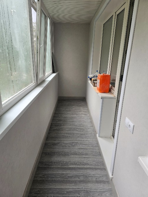 Остекленный балкон с серым полом и минималистичным дизайном