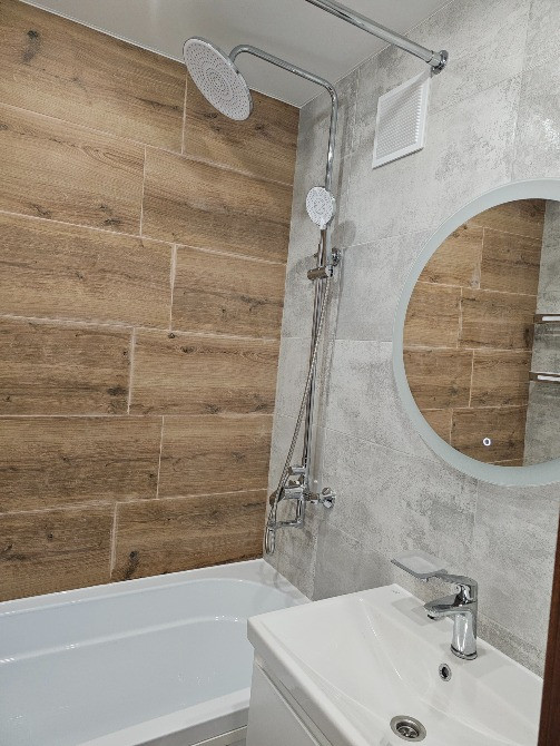 Современный интерьер ванной комнаты с плиткой под дерево и удобной ванной