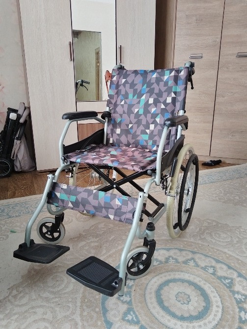 Түсті өрнегі бар мүгедек арбасы, жиһазбен безендірілген бөлмеде кілемде тұр.