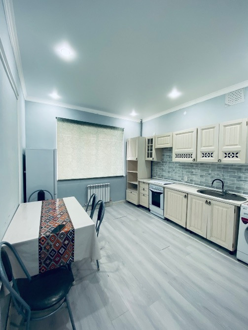 Светлая кухня с обеденным столом и техникой