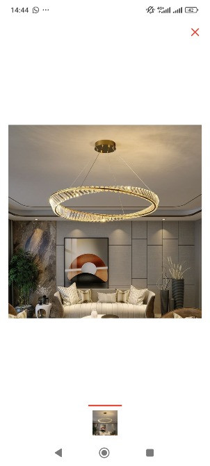 Современная люстра с кольцевым дизайном и светодиодным освещением в интерьере гостиной с мягкой мебелью и декоративными элементами