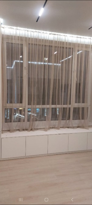 Светлая комната с жалюзи и панорамными окнами, оформленная в минималистическом стиле