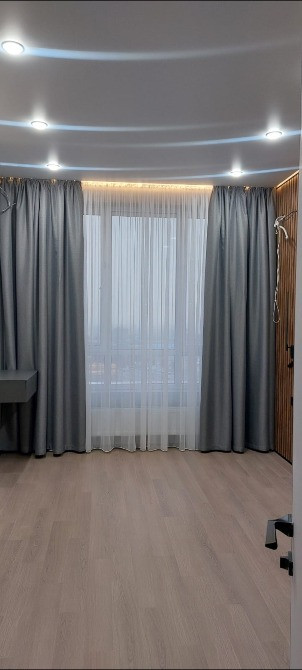 Современный интерьер комнаты с серыми шторами и деревянной дверью