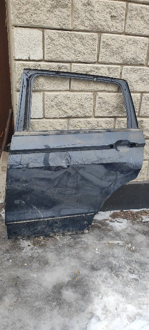 Тас қабырғаның жанына қалдырылған қара көліктің есігі