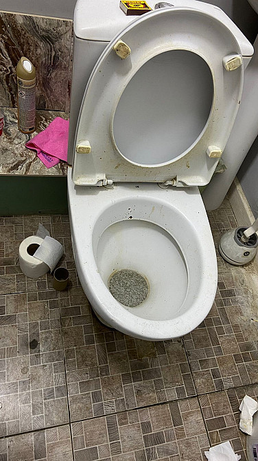 Унитаз с открытой крышкой и небольшими загрязнениями внутри