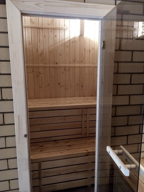 Вход в парную с зеркальной дверью и деревянной отделкой внутри