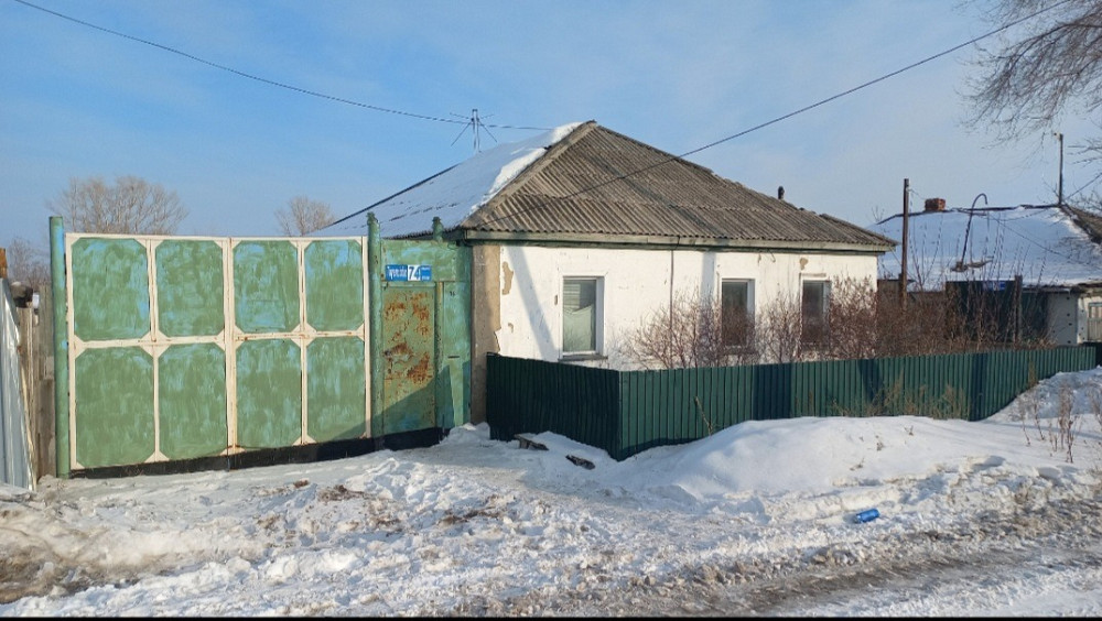 Заброшенный дом с крышей и воротами в снежном пейзаже зимой