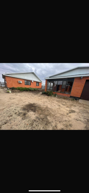 Бұлтты аспан фонында бір аулада орналасқан екі үй