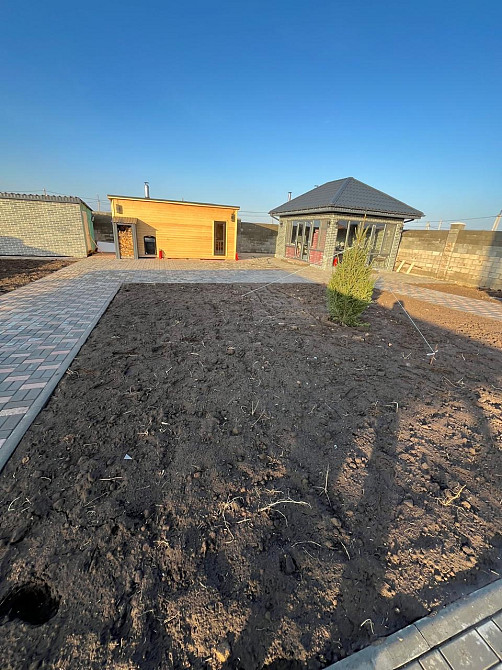 көк аспан фонында жасыл газон және үйлермен учаске