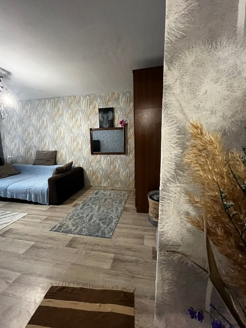 Диван мен қабырғадағы декор элементтерімен безендірілген жайлы бұрыштың көрінісі