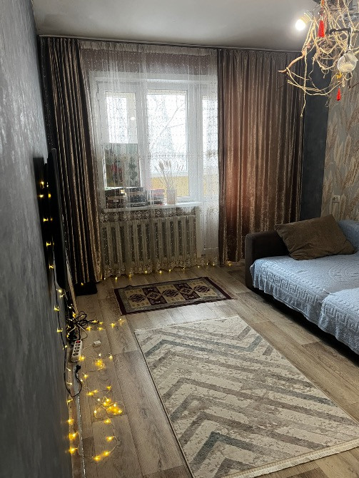 Современный интерьер бөлмесі, диван және кілем, гирляндалармен безендірілген