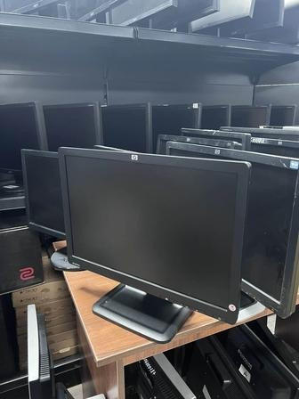 HP мониторлары техникалық дүкендегі сөреде, қара түсті, көп мөлшерде бар.