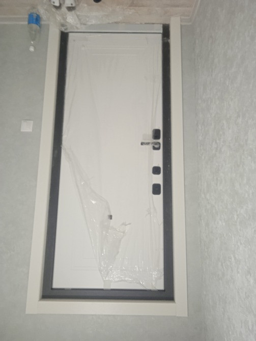 Сұр қабырғалары бар интерьердегі қорғаныс пленкасы бар есік