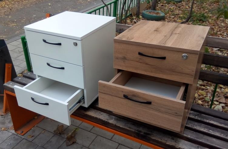 Екі тумбочка: біреуі ақ түсімен ашық жәшіктермен, екіншісі ағаштан