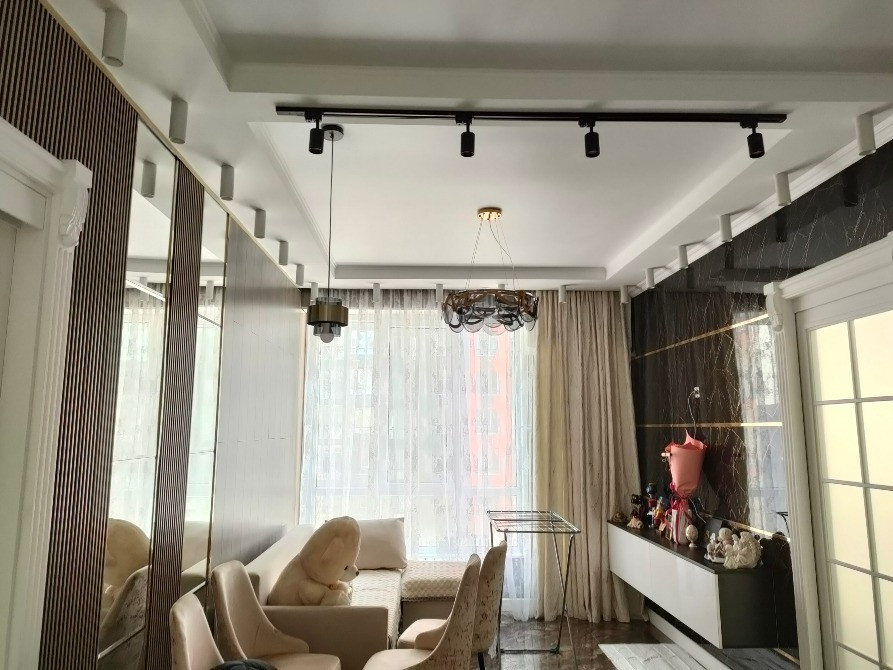 Заманауи жарықтандыру мен жұмсақ мебельмен стильді бөлме интерьеры