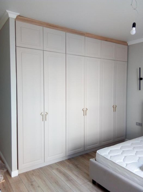 Шкаф с дверцами и золотыми ручками, располагающийся над кроватью