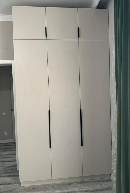 Светлый шкаф с высокими дверцами и черными ручками