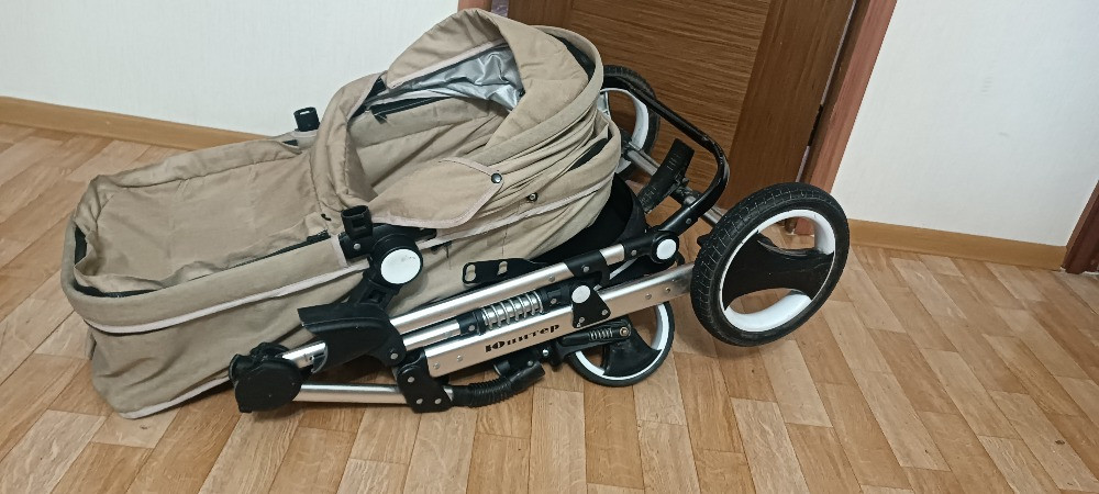 Сложенная детская коляска на полу
