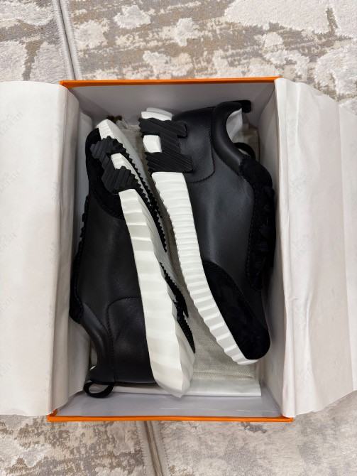 Қара кроссовкалар ақ және қара табаны бар қорапта