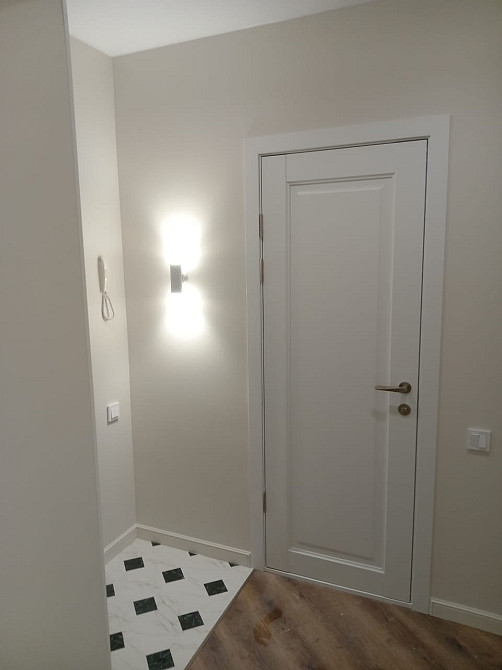 Заманауи кіреберістің интерьері ақ есігімен және қабырға шамымен