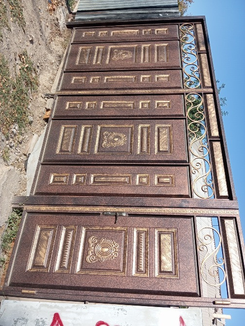 Декоративті элементтері мен металл каркасымен безендірілген кованые ворота ашық аспан фонында.