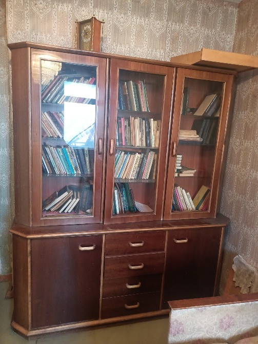 Книжный шкаф с коллекцией книг и ящиками для хранения в комнате с обоями