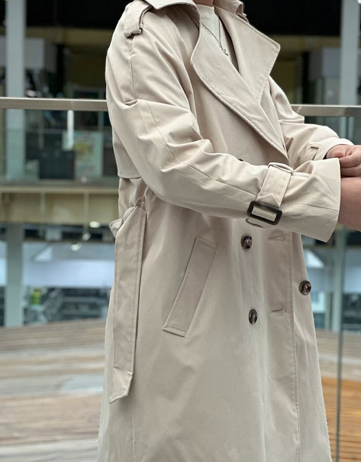 Бежевое пальто с приталенным силуэтом, акцент на детали рукава и пуговицы