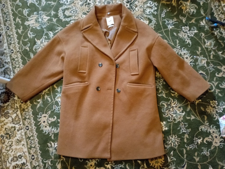 коричневое пальто на зеленом ковре