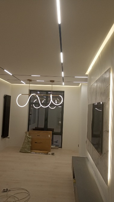 Кең бөлмедегі стильді жарықтандырғыш және қабырғадағы теледидар