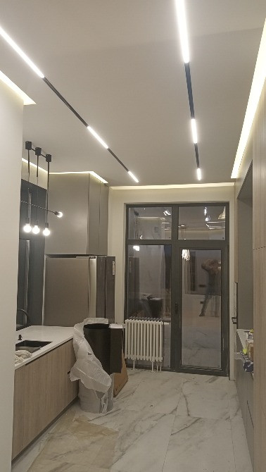 Интерьер кухни с современными светильниками и большими окнами