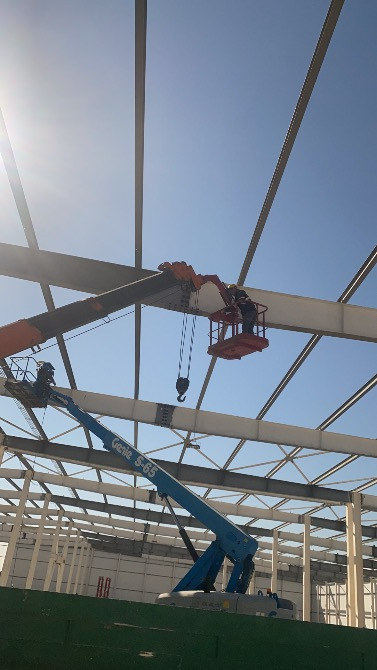 Рабочие используют подъемники для установки конструкций на строительной площадке с металлическим каркасом
