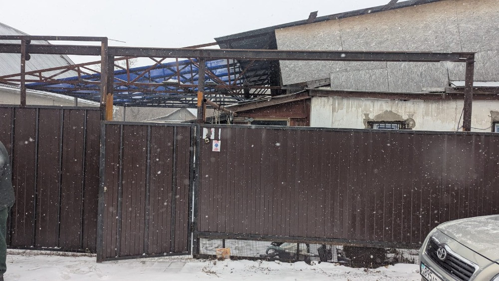 Заметная калитка во дворе с снегом и конструкцией крыши