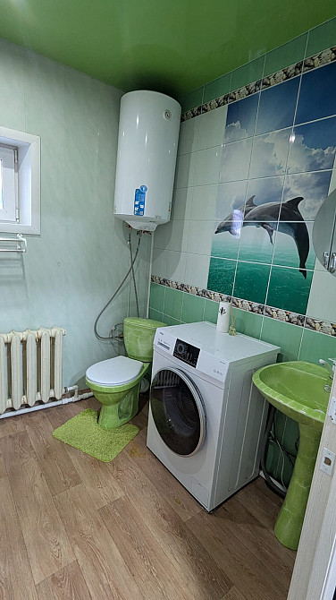 Ванная комната с стиральной машиной и сантехникой на фоне зеленых стен