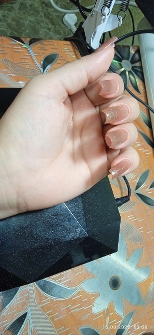 Изображены руки с ухоженными ногтями среднего размера, светлый маникюр, на фоне цветного стола