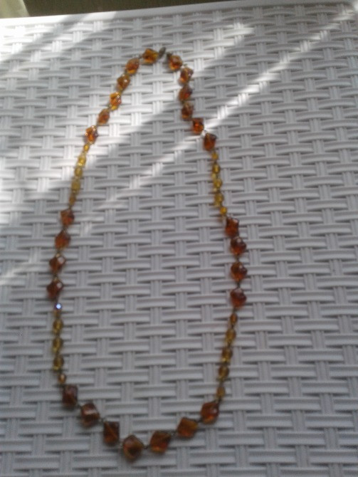 Текстурланған фондағы янтарь түсті моншақтан жасалған ожерелье