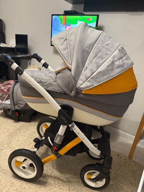 Коляска с уникальным дизайном, вид сбоку, расположенная в комнате с телевизором