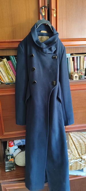 Пальто темно-синего цвета на вешалке с двумя рядами пуговиц