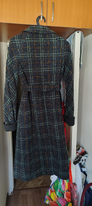 Пальто с крупной клеткой, одетое на вешалке, вид сзади