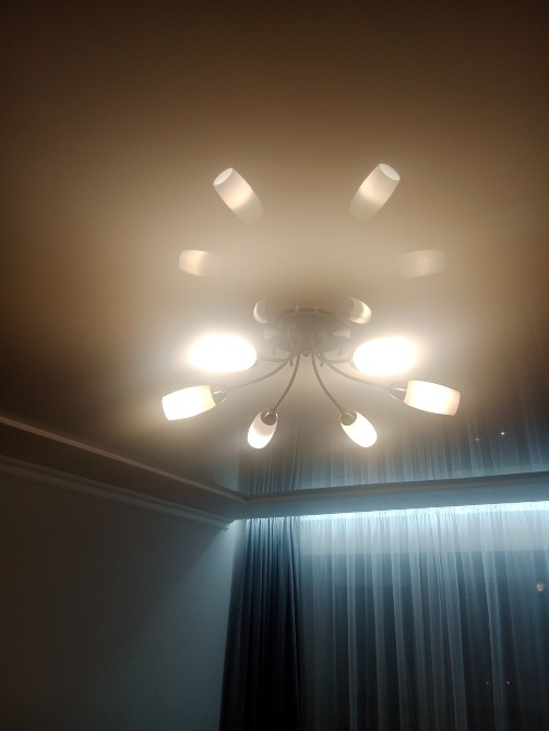 Заманауи төбе жарығы бар бөлмедегі жарықтандыру, жарықтандырғыштар ақ абажурлармен жабдықталған және жайлы атмосфераны қалыптастырады.