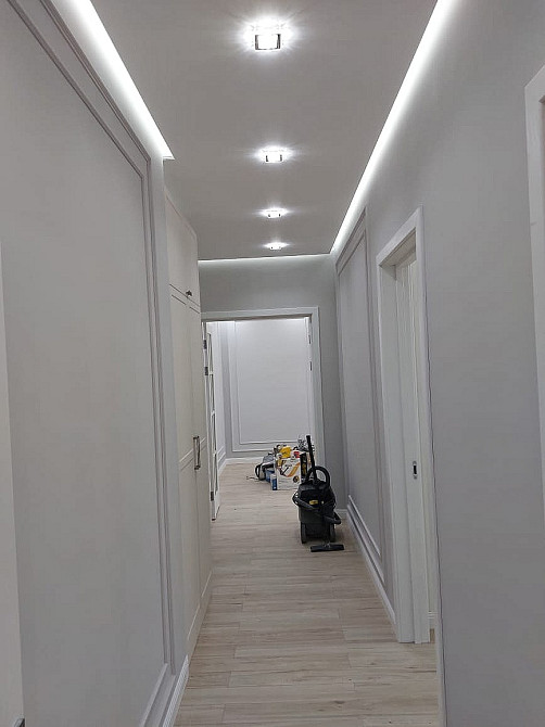 длинный коридор с современным дизайном, белыми стенами и потолочными светильниками