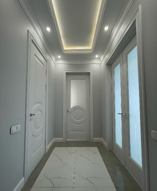 светлый коридор с дверями, гладким потолком и плиткой на полу