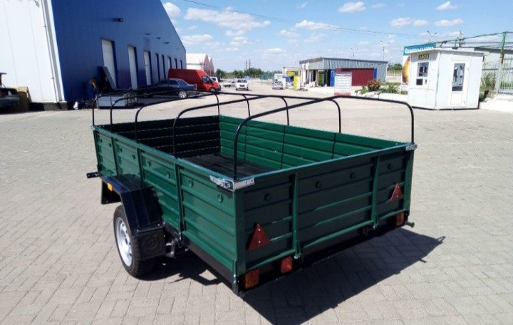 Открытый прицеп зеленого цвета с ограждением